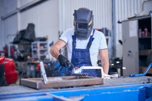 Male worker in welding helmet welding metal in garage