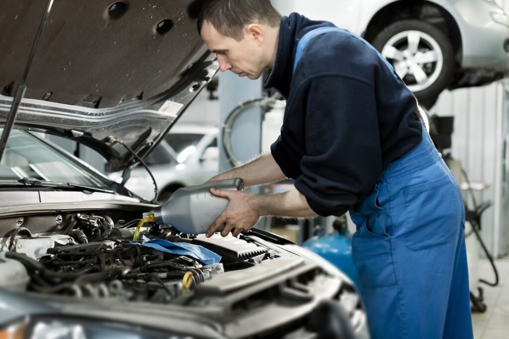 Service mechanic pouring new synthetic or organic oil lubricant into the engine