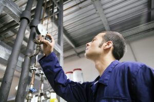 Technician working in a technical room looking at gauge